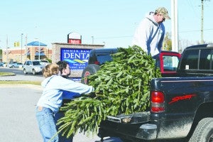 MIKE VOSS | DAILY NEWS : Ben Crawford (left) and Kevin White (center) help Bill Gales load a Christmas tree into the bed of Gales’ pickup truck Friday. 