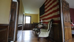 VAIL STEWART RUMLEY | DAILY NEWS ABOVE STAIRS: The woodwork leading up the stairwell to the upstairs has never been painted at Bellefont Plantation. Here, Boyd has arranged a seating area beneath an American flag she purchased at antiques store. The flag, with 46 stars, only flew for four years — from 1908 to 1912. 