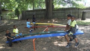 JONATHAN ROWE | DAILY NEWS SEESAW: Children enrolled in the Purpose of God Annex Outreach Center Summer Program play together on seesaws during recreational time. 
